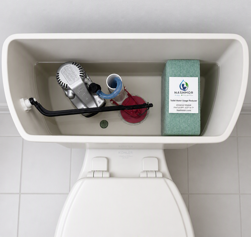 Top-down view of a toilet tank with the lid open, showing a toilet water usage reducer block by Nashmor placed next to other toilet parts inside the tank.